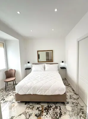 a white bedroom with a bed and a chair at Callas Luxury Apartment in Rome