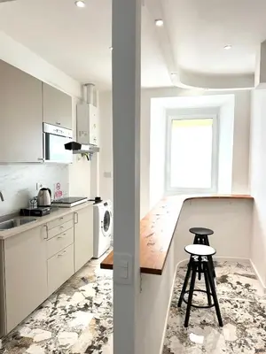 a kitchen with white cabinets and a stool in it at Callas Luxury Apartment in Rome