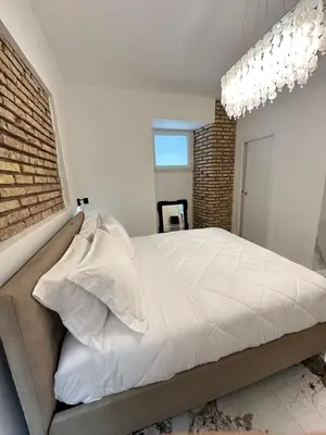 a bedroom with a white bed and a brick wall at Callas Luxury Apartment in Rome