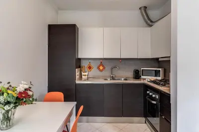 a kitchen with white cabinets and a table with orange chairs at Lovely flat near Vaticano in Rome