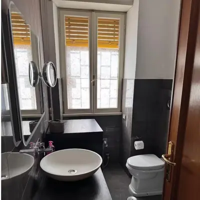 a bathroom with a sink and a toilet and mirrors at Colle Aurelio Home in Rome