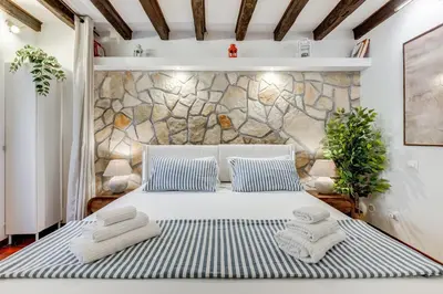 a bedroom with a white bed with blue and white pillows at Colosseum Loft, Rustic-modern charm in Rome