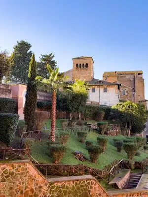 a garden with palm trees and a building in the background at Zen 31 - Colosseum cozy apartment in Rome