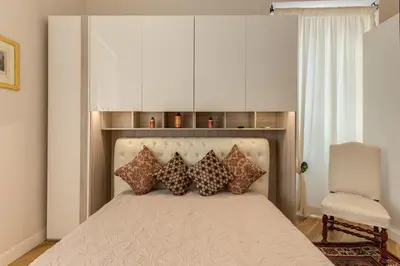 a bedroom with a bed with pillows and a chair at Casa Claudia Giulio Cesare in Rome