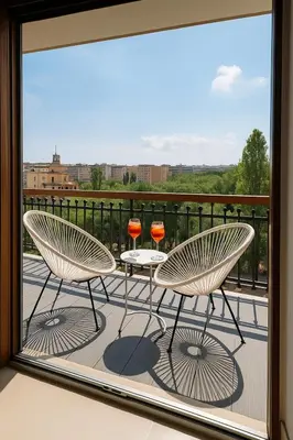 two chairs and tables on a balcony with a view at TraStella, Trastevere di charme, balcone & hammam in Rome
