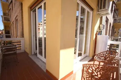 a balcony with two chairs and a building with windows at Claudia 2BR Holiday Home in Rome