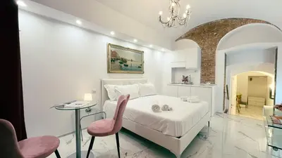 a white bedroom with a bed and a pink chair at Domus Jana 30 in Rome