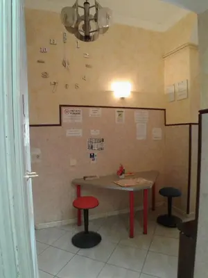 a table and two stools in a room with a clock on the wall at Cressy in Rome