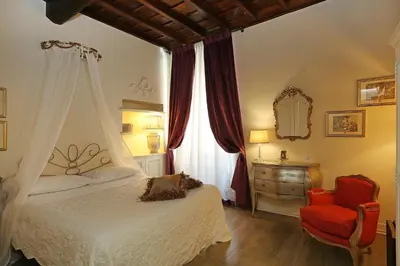 a bedroom with a bed and a chair and a window at Piazzetta de' Monti Suites in Rome