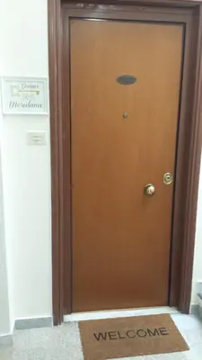 a brown door with a welcome mat in front of it at Domus Merulana Bed and Breakfast in Rome