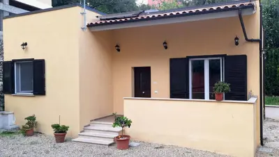 a yellow house with black shutters and potted plants at San Paolo Hideout in Rome