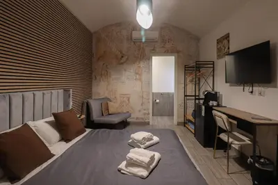 a bedroom with a bed with a desk and a television at Essenza House Porta Pia in Rome