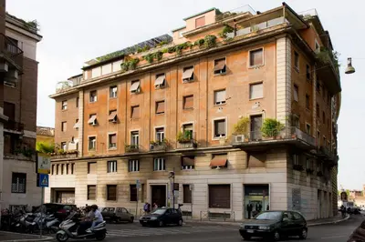 a large brick building on a city street with cars at Ripense In Trastevere in Rome