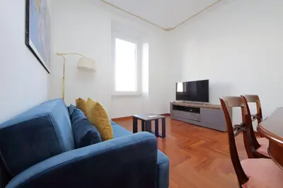 a living room with a blue couch and a tv at 4BNB - St. Peters Dome Apartment in Rome