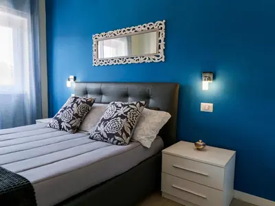 a blue bedroom with a bed with a mirror on the wall at Saint Peter Welcoming Apartment in Rome
