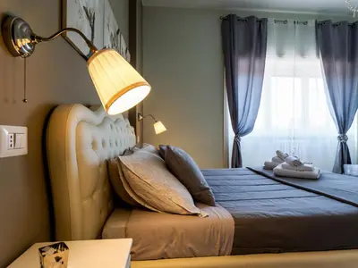 a bedroom with a bed with a lamp and a window at Saint Peter Welcoming Apartment in Rome