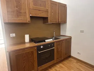 a kitchen with wooden cabinets and a sink and a stove at San Vitale 18 by GHOR in Rome
