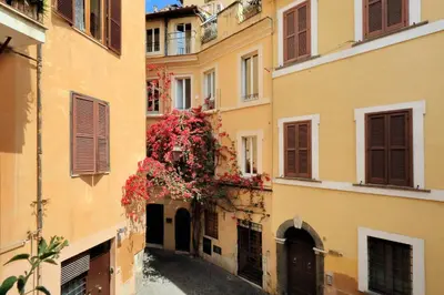 an alley between two buildings with red flowers at Bollo in Rome