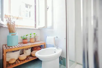 a bathroom with a toilet and a shelf with plants at A Secret Corner in Rome