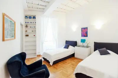a bedroom with two beds and a chair at S.Andrea in Rome