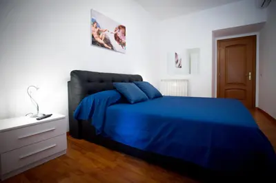 a bedroom with a blue bed and a white wall at Vatican Art Place in Rome