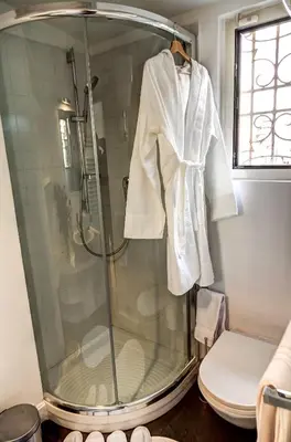 a shower in a bathroom with a toilet and a robe at Good Life Monti in Rome