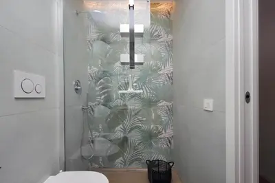 a bathroom with a shower with a green leaf wallpaper at Il Villino di Adelchi by DomusDimore in Rome