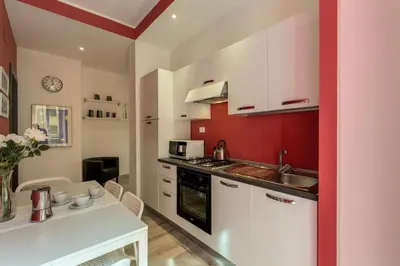 a kitchen with white cabinets and a red wall at M&L Apartment - Caracalla Holiday in Rome