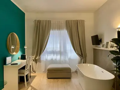 a bathroom with a tub and a desk and a window at Le Coq Suites in Rome