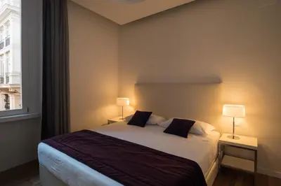 a bedroom with a bed with two lamps and a window at Trevi Elite Rome in Rome