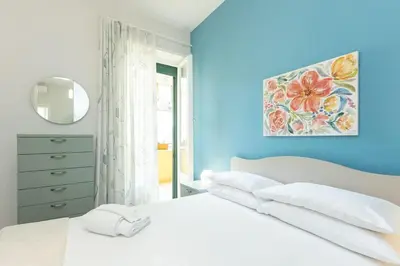 a blue bedroom with a white bed and a mirror at Nuovo appartamento ben collegato con il centro in Rome