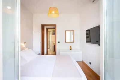 a white bedroom with a white bed and a tv at Quieto alloggio vicino stazione e metropolitana in Rome