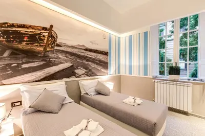 a bedroom with two beds and a painting of a boat at Grand Tour Rome Suites - Liberty Collection in Rome