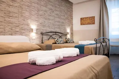 a room with three beds and a brick wall at Domus Castroni Pompeo Magno in Rome