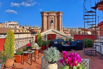 a rooftop patio with plants and tables and a clock tower at Spagna Penthouse in Rome