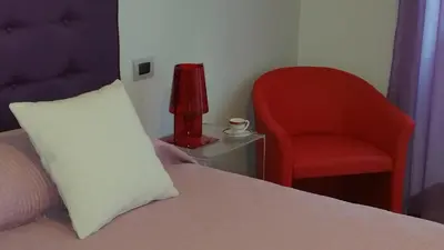 a bed with a pillow and a red chair at La Casa Del Pigneto in Rome