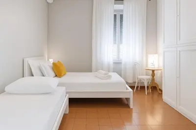 a white room with two beds and a table at èROMA - ESQUILINO Apartment in Rome