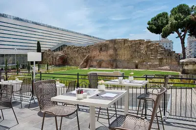 a patio with white tables and chairs with a view ofartifacts at NH Collection Palazzo Cinquecento in Rome