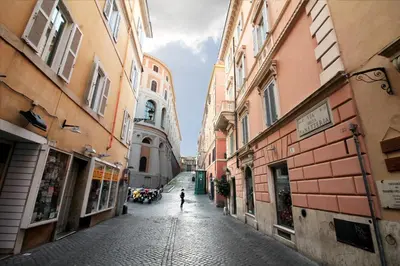 a person walking down an alley between buildings at The Trevi Fountain and Spanish Steps Experience in Rome