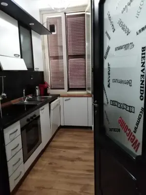 a kitchen with white cabinets and a black refrigerator at YourStay@Rome Coliseum in Rome