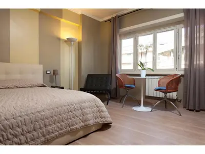 a bedroom with a bed and two chairs and a table at Alex's Guest House in Rome