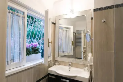 a bathroom with a sink and a mirror and a window at Margutta's Garden in Rome