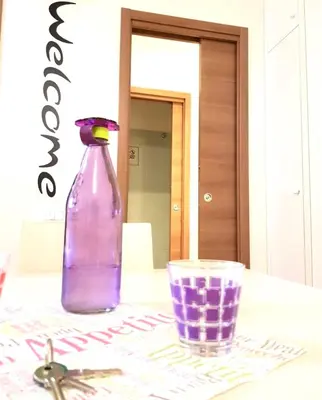 a purple bottle sitting on a table next to a glass at Vatican Area Flat in Rome