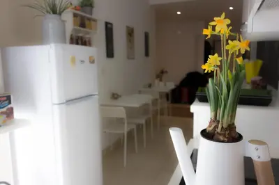 a kitchen with a white refrigerator and a vase with yellow flowers at Coffee And The City in Rome