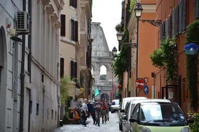 a group of people walking down a street with cars at Studio Cardello Colosseum in Rome