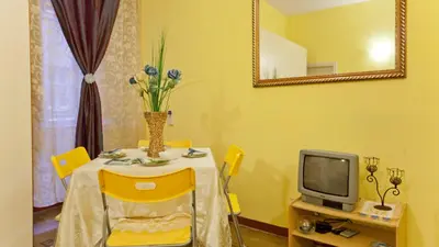 a yellow dining room with a table and a tv at Rental in Rome Sardegna Apartment in Rome