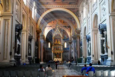 a group of people sitting in a large cathedral at Viale del Colosseo in Rome