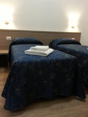 two beds with blue comforter and towels on top at Marziah Inn in Rome