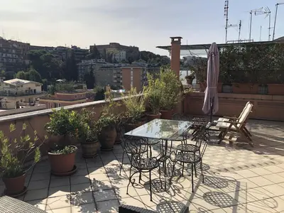 a balcony with a table and chairs and an umbrella at Angelo Emo Terrace in Rome