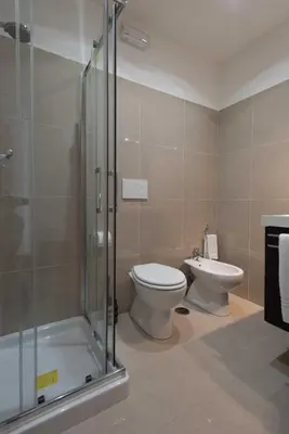 a bathroom with a toilet and a glass shower at Audrey Rooms in Rome